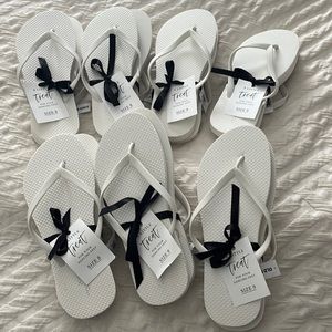 7 pairs of white flip flops in various sizes